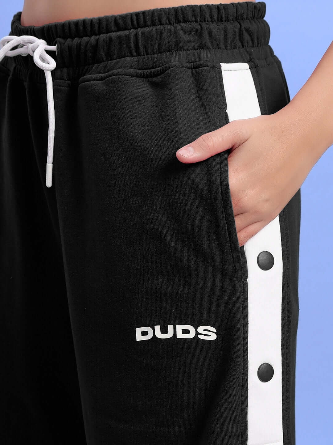 Close-up of WOMEN'S EZEL regular fit black shorts with waistband and pockets, featuring a white stripe and button detail.