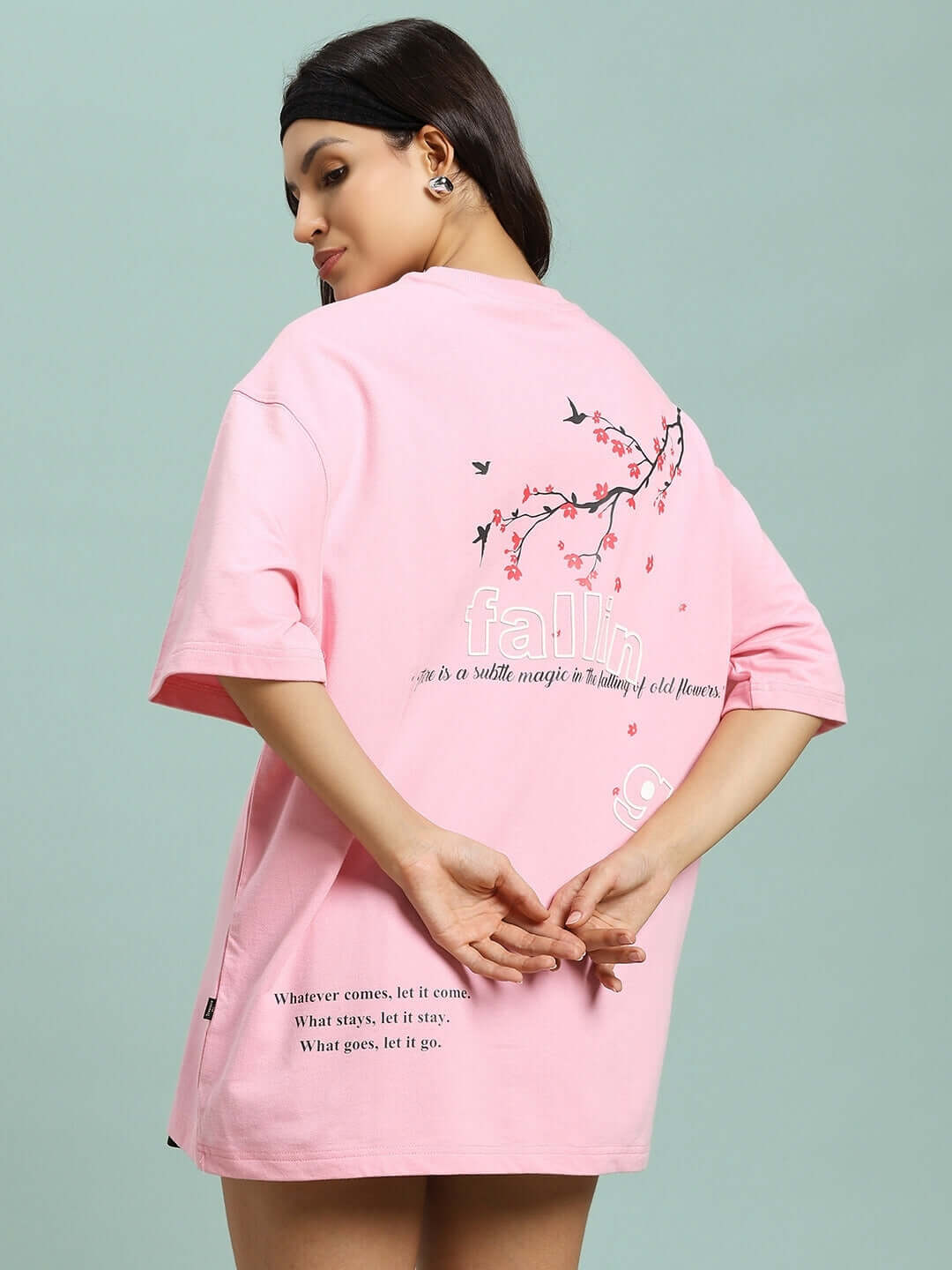 Model wearing pink Women's Falling Flower T-shirt with floral design, made from premium cotton fabric, showcasing back print details.
