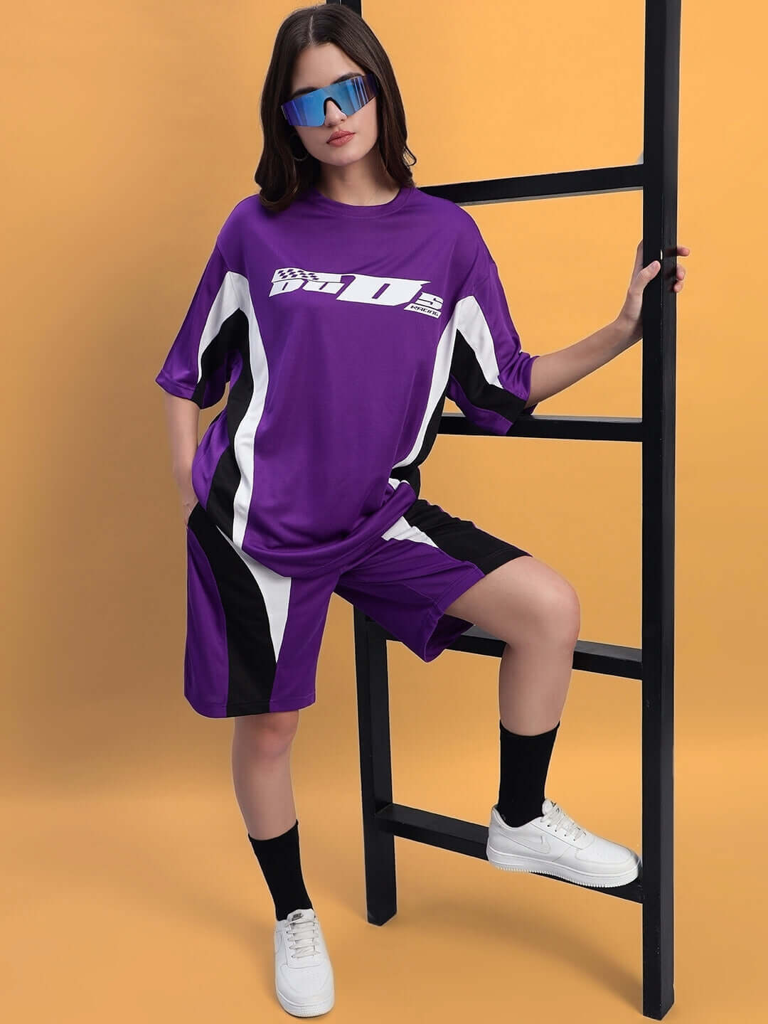 Model wearing WOMEN'S FIFA COLORBLOCK CO-ORD SET PURPLE with sporty design, posing against a ladder.