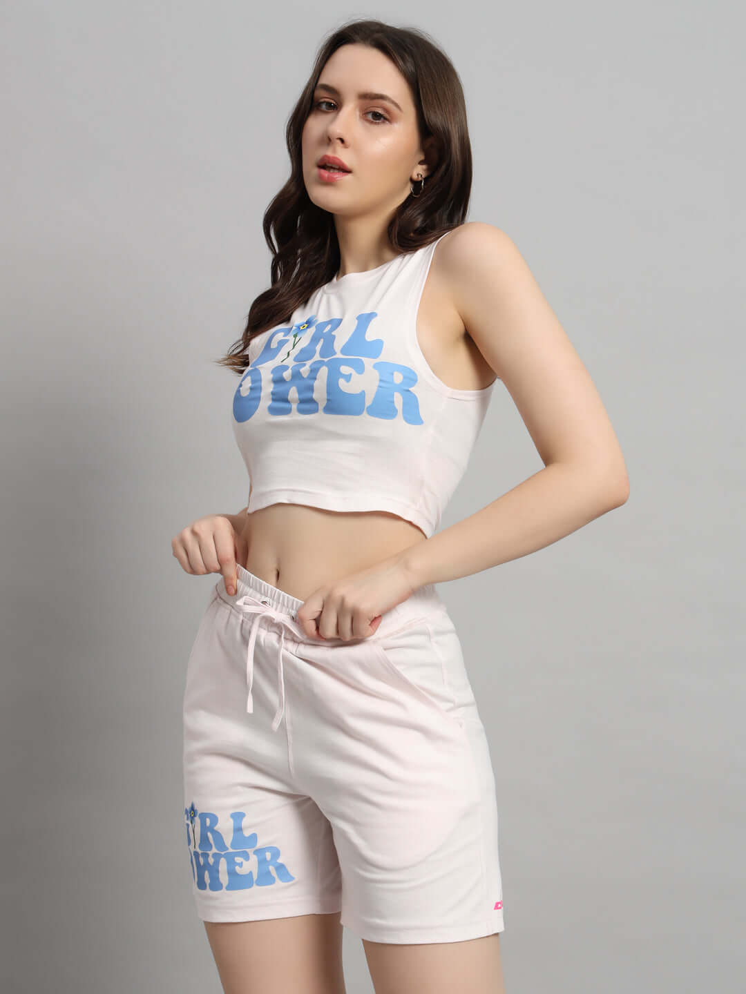 Model wearing Women's Girl Power Co-ord Set in Baby Pink, featuring a crop top and shorts with bold print, made from cotton and elastane.