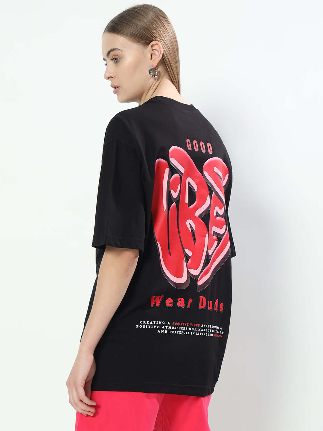 Woman wearing a black oversized Good Vibes T-shirt by Duds, showcasing bold red lettering on the back.