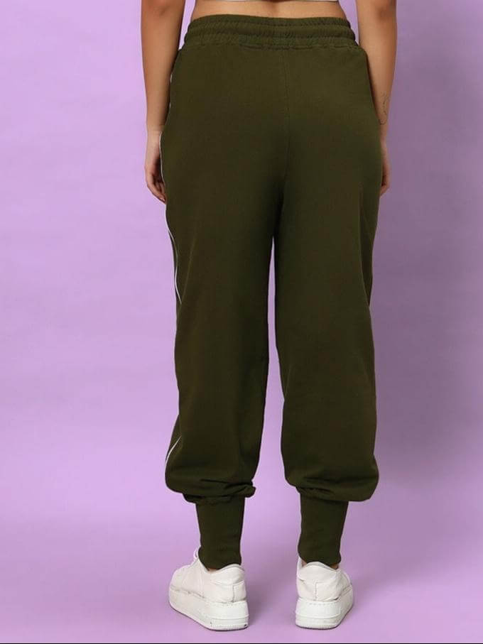 Back view of women's olive green joggers with elastic waistband and cuffs, worn with white sneakers on a purple background.