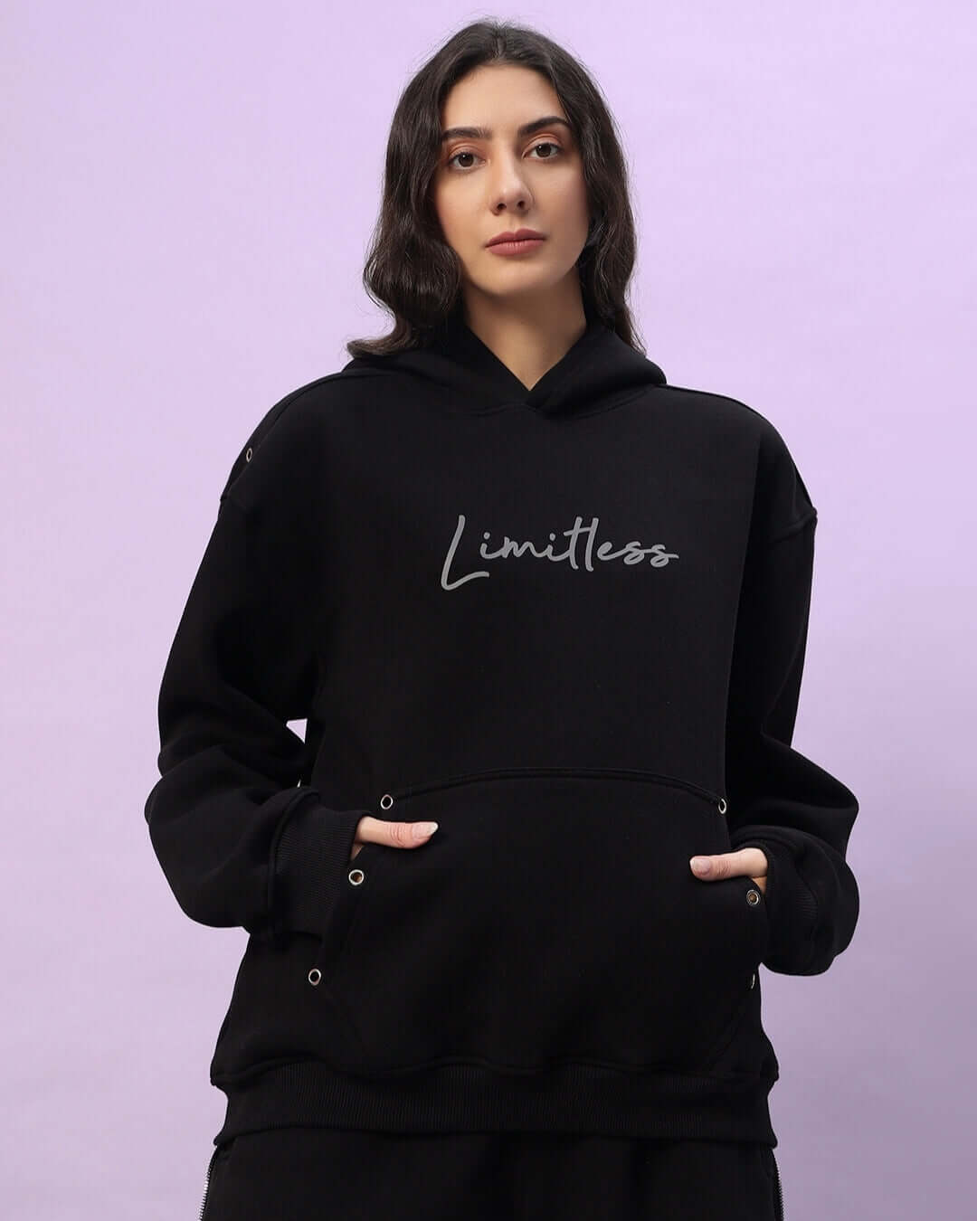 Woman wearing black Women's Limitless Fleece Reflector Hoodie with stylish reflector detailing, perfect for casual or outdoor activities.