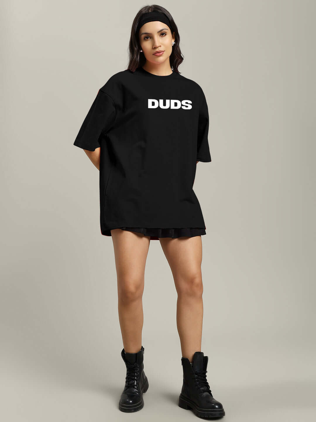Model wearing women's oversized black T-shirt labeled 'DUDS', styled with sturdy black boots, ideal for casual fashion.