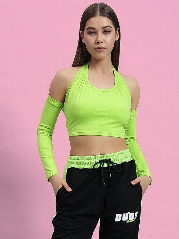 Woman wearing WOMEN CLUTCH CROP-TOP NEON GREEN with black pants on pink background.