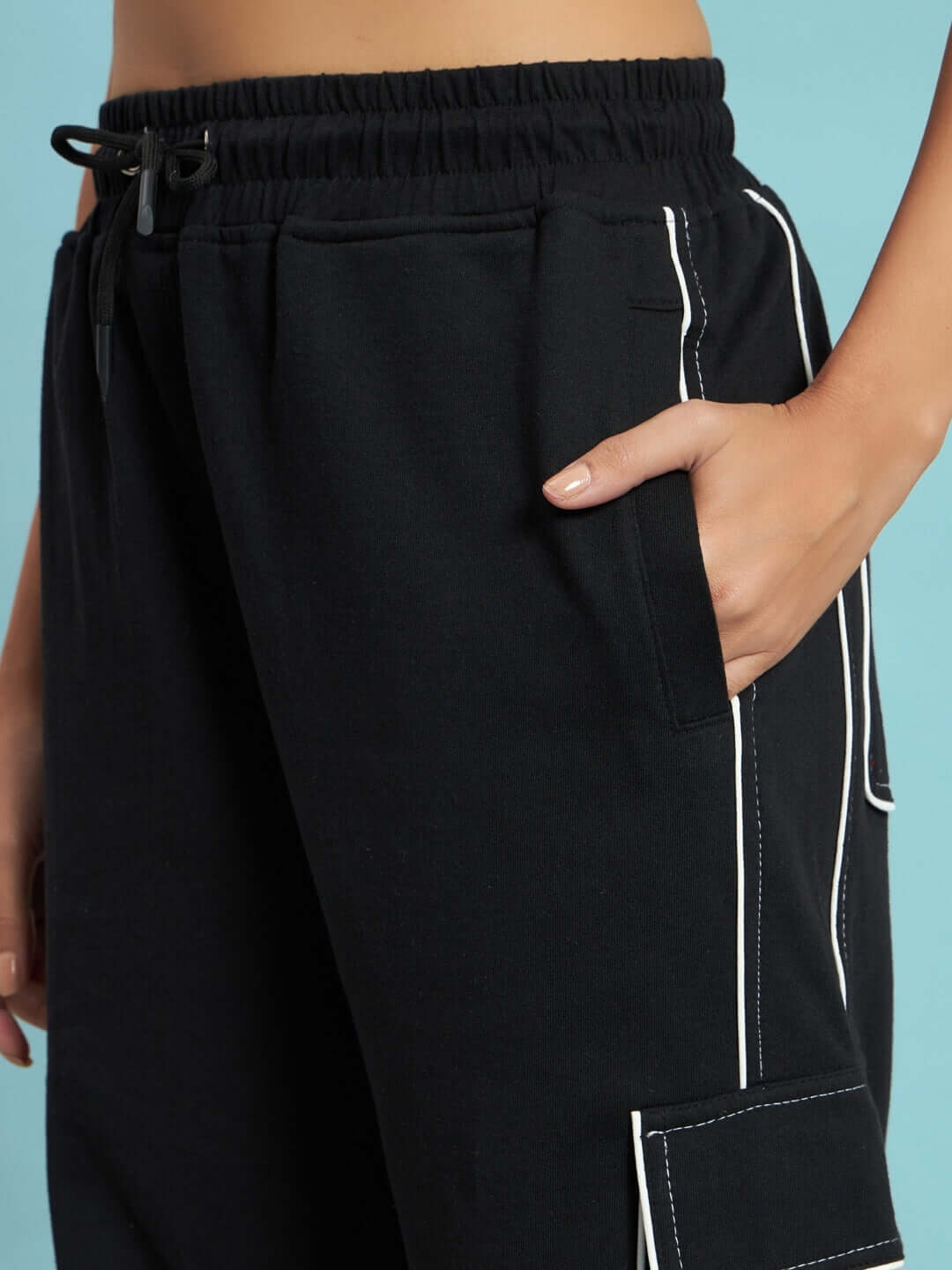Close-up of women's black cargo pants with contrast stitching and pockets, showcasing craftsmanship by DUDS.