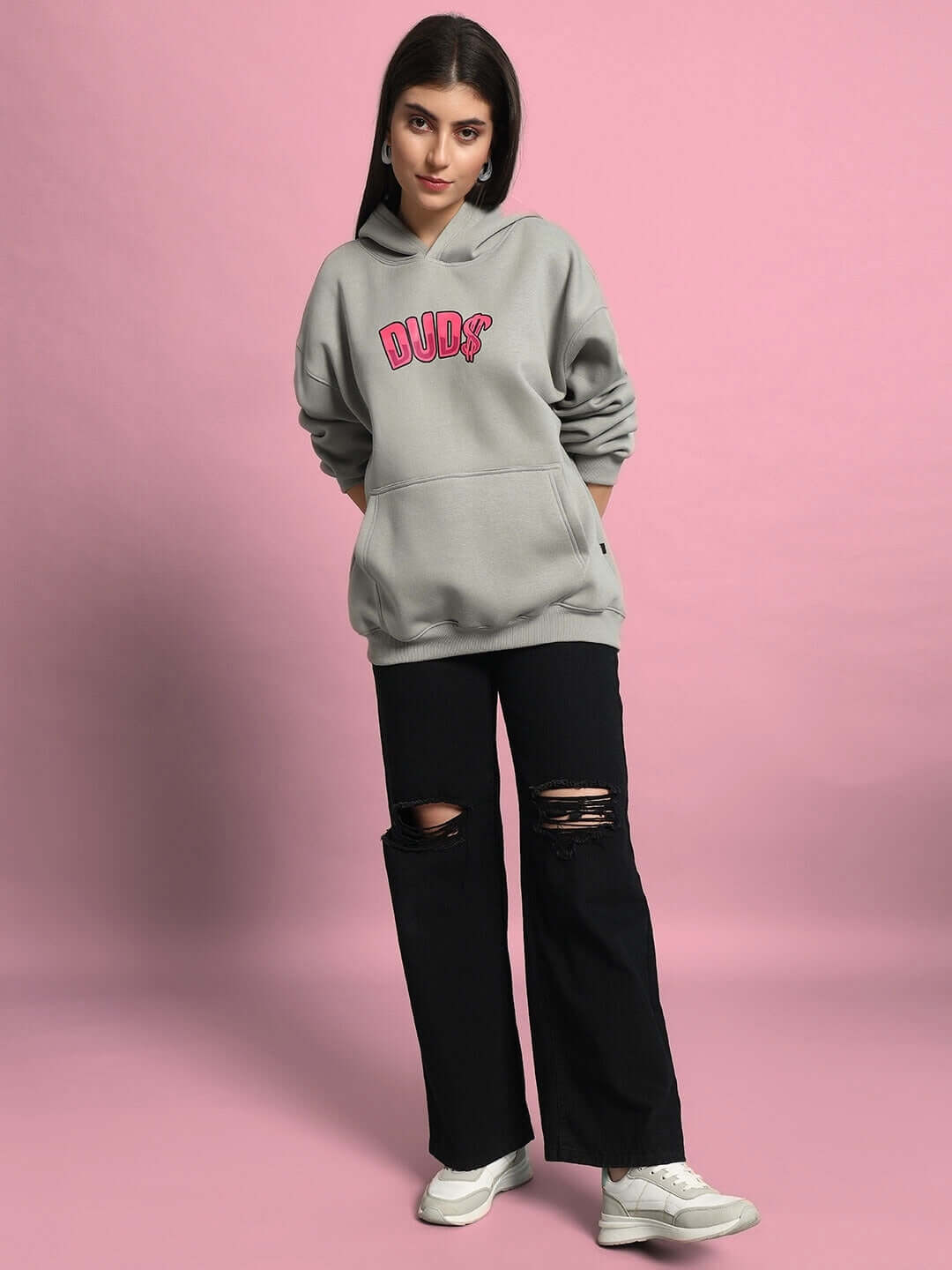 Woman wearing WOMEN PINK PANTHER OVERSIZED HOODIE GREY by DUDS, standing against a pink background.