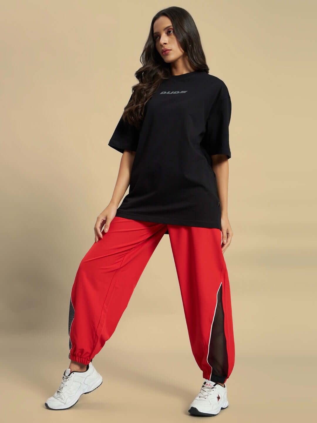 Woman wearing black shirt and red WOMEN'S PLEXUS JOGGERS from DUDS, showcasing sporty fashion style.