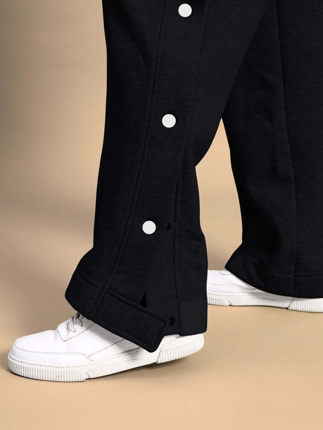 Close-up of black pants from WOMEN POLAR COLORBLOCK CO-ORD BLACK PEACH, featuring white buttons and paired with white sneakers.