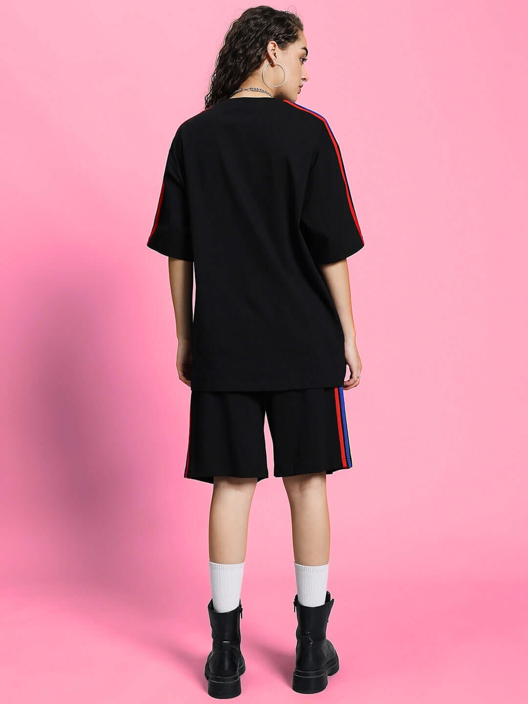 Back view of model wearing WOMEN'S RAINBOW SUMMER CO-ORD SET BLACK with bold rainbow detailing against a pink background