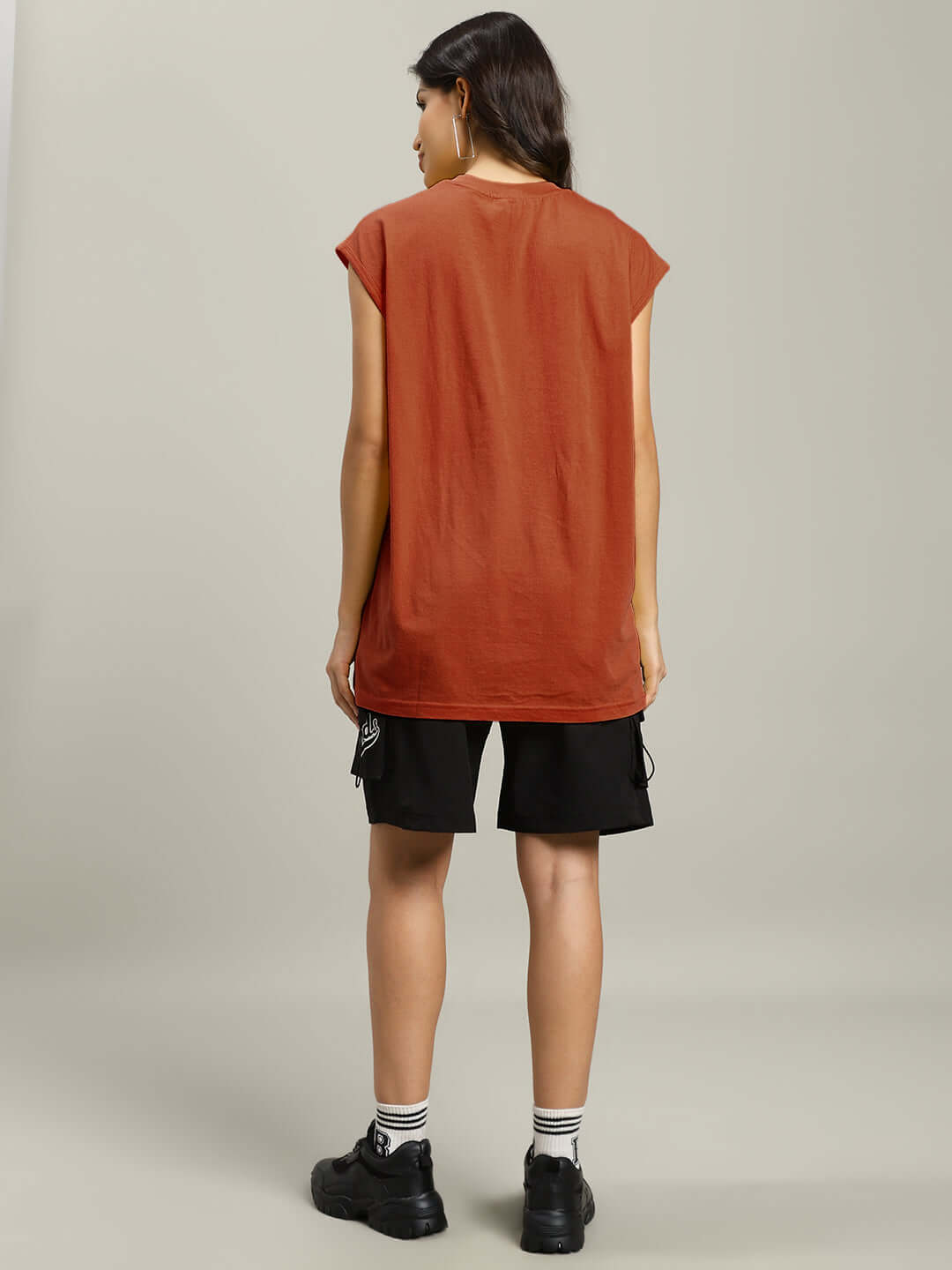 Back view of a woman wearing a brown women's Scooby gym t-shirt and black shorts, showcasing casual and comfortable style.