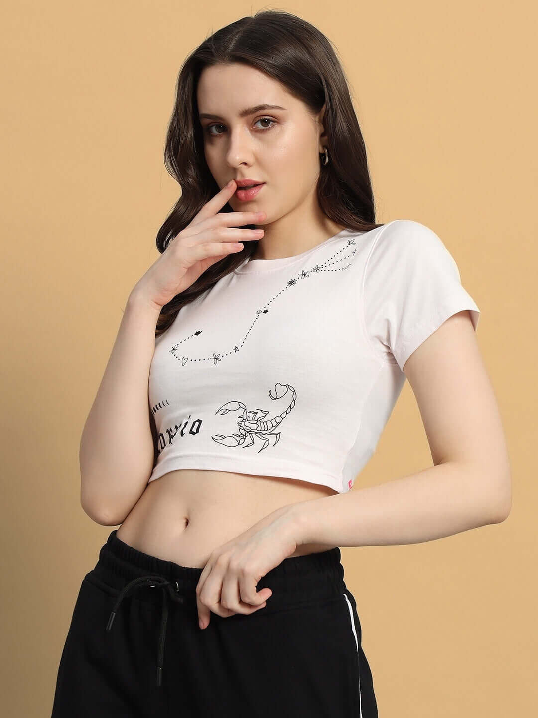 Model wearing WOMEN SCORPIO CROP-TOP BABY PINK with a Scorpio print in a stylish indoor setting.