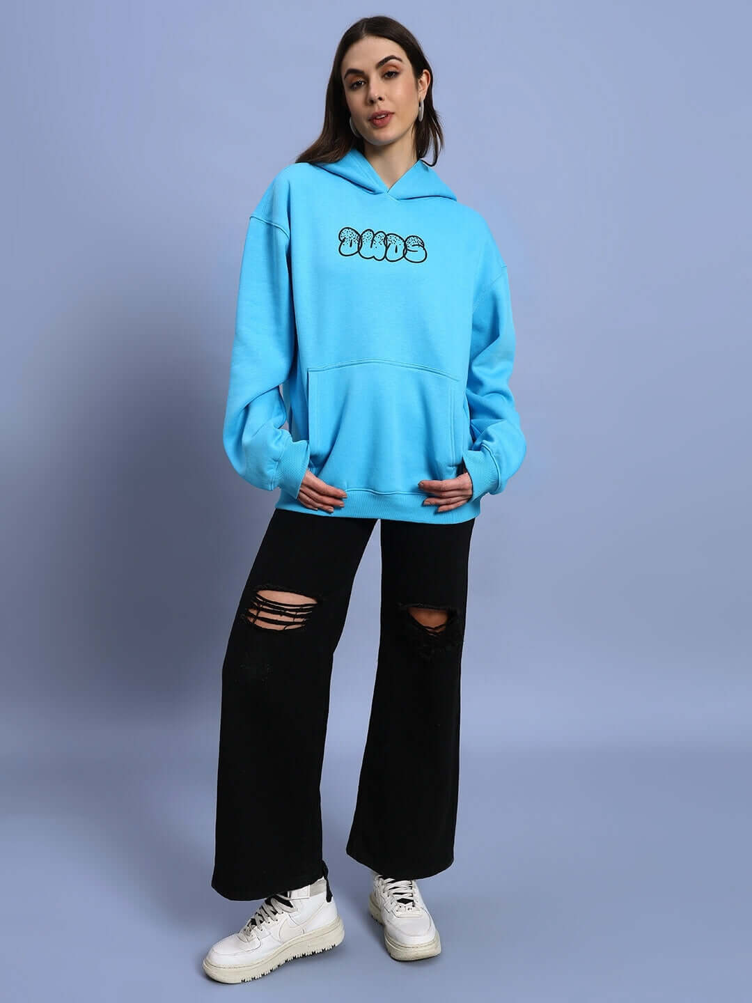 Woman modeling WOMEN SHARKWAVE FLEECE OVERSIZED HOODIE LIGHT BLUE with ripped black jeans, showcasing streetwear style.