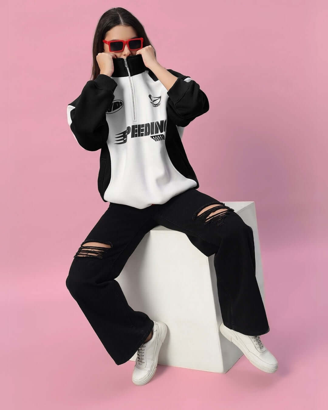 Model wearing Women's Speeding Colorblock Jacket in black with ripped jeans, styled with red sunglasses against a pink background.