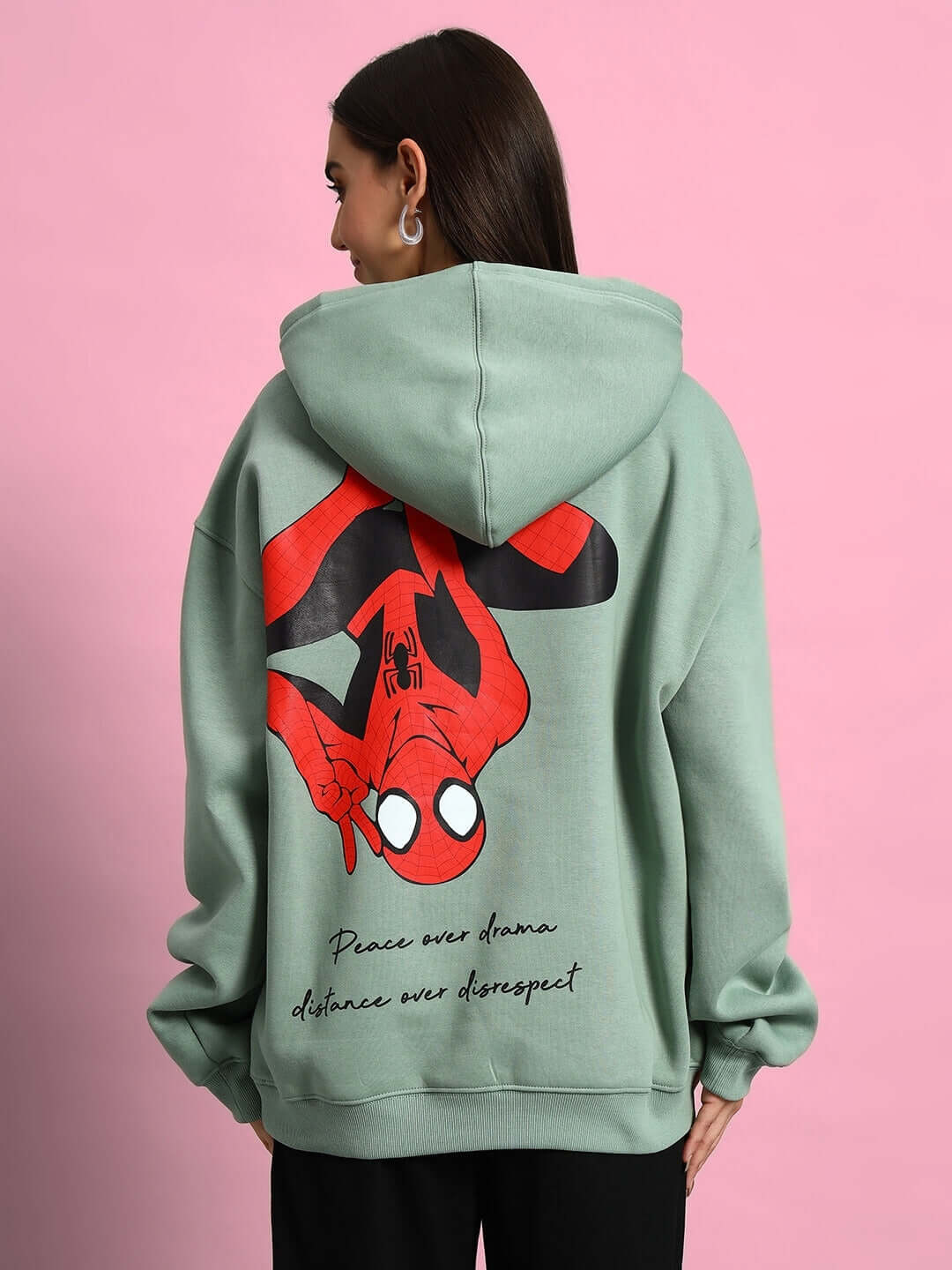 Woman wearing WOMEN SPIDERMAN OVERSIZED FLEECE HOODIE JADE GREEN with Spiderman graphic on the back.
