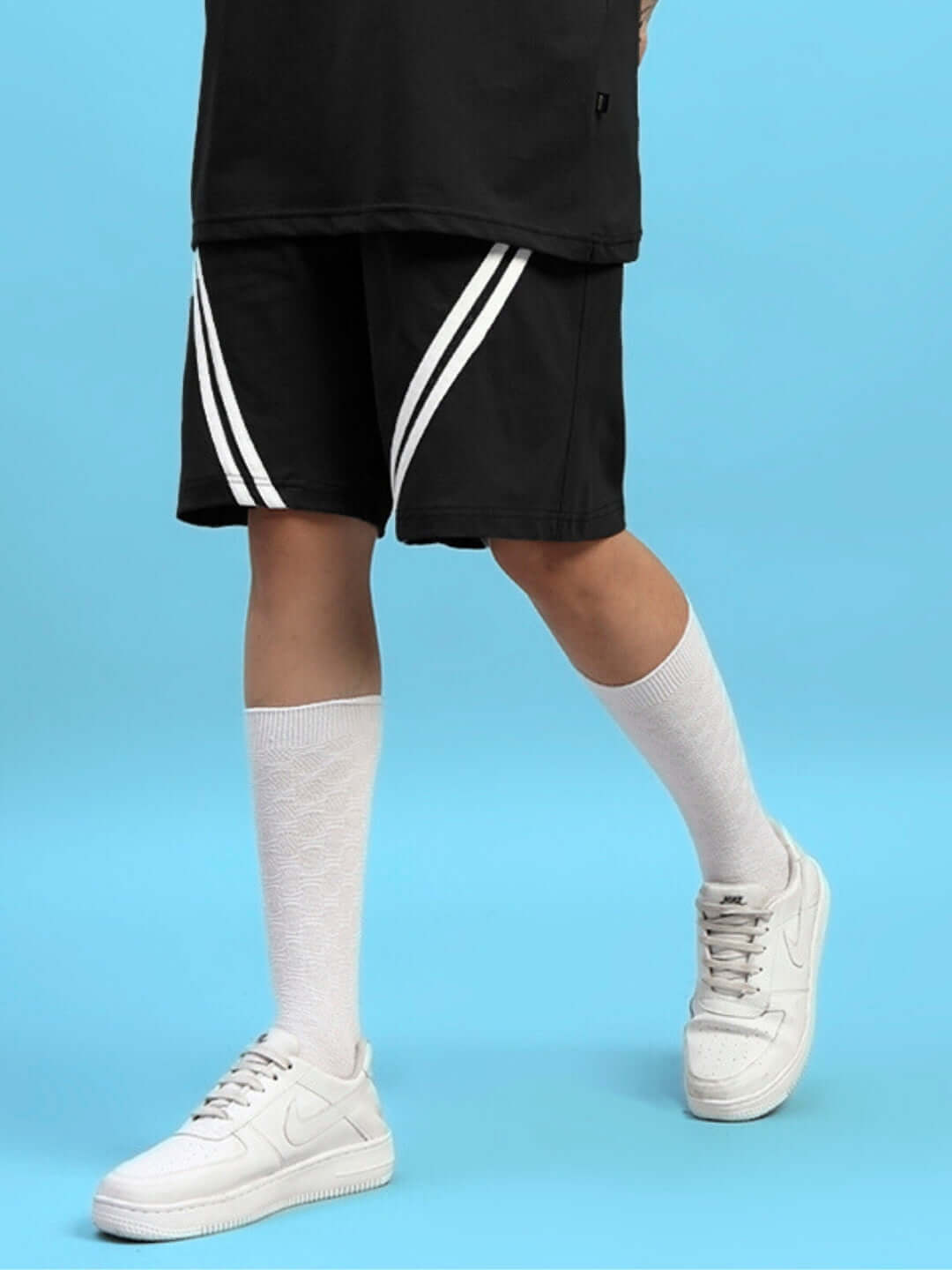 Model wearing Women's Star Jumper Regular Fit Shorts in black, paired with white socks and sneakers. Perfect for a stylish casual look.