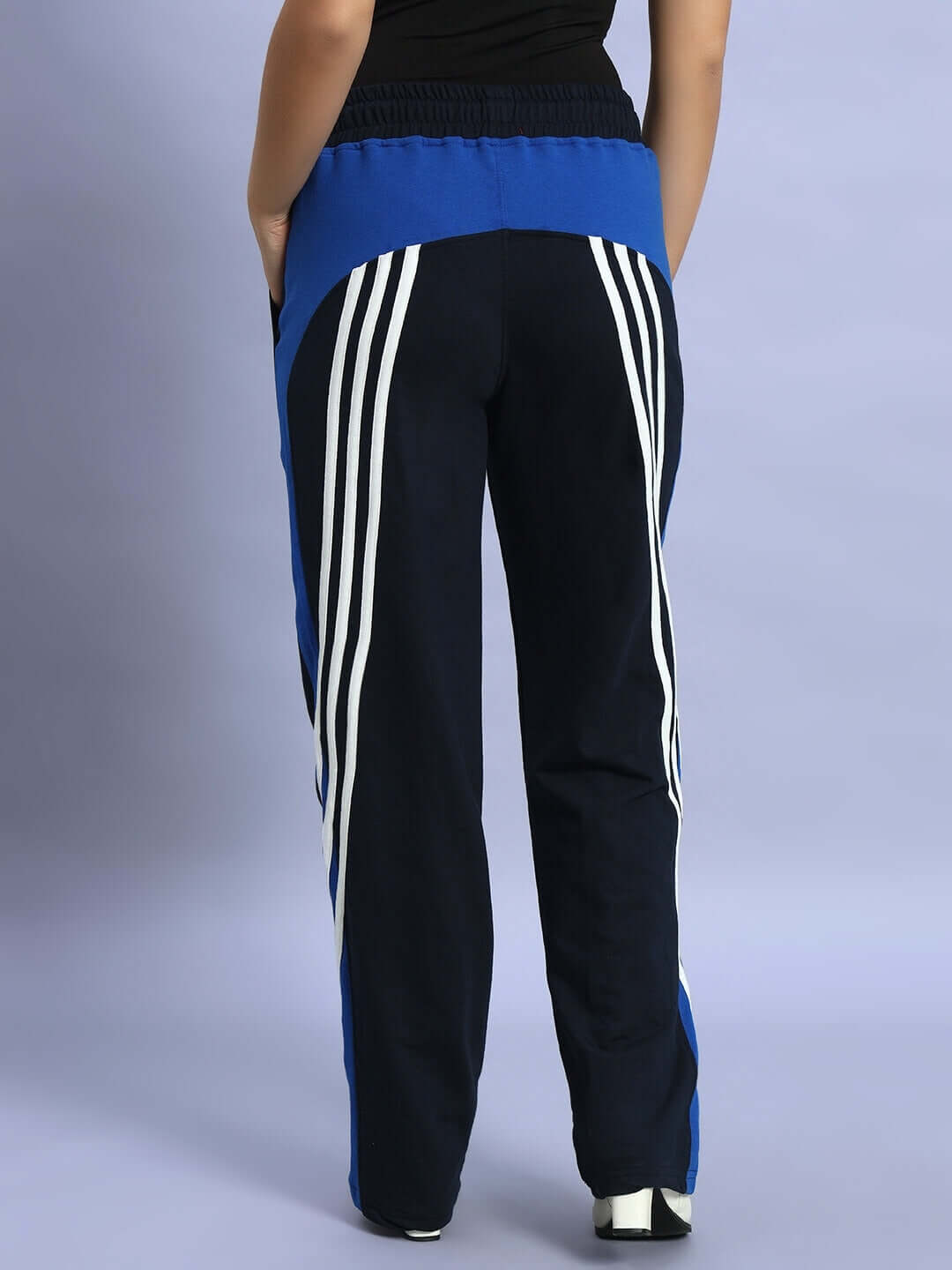 Back view of women's navy blue relaxed-fit joggers with white stripes, showcasing design and comfortable fit.