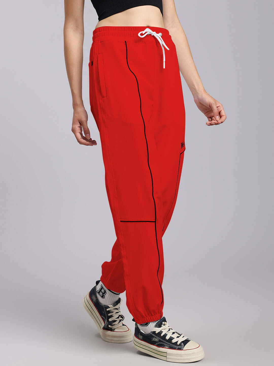 Woman wearing WOMENS TOKYO RELAXED FIT JOGGERS RED with sneakers, featuring relaxed silhouette and breathable fabric for comfort.