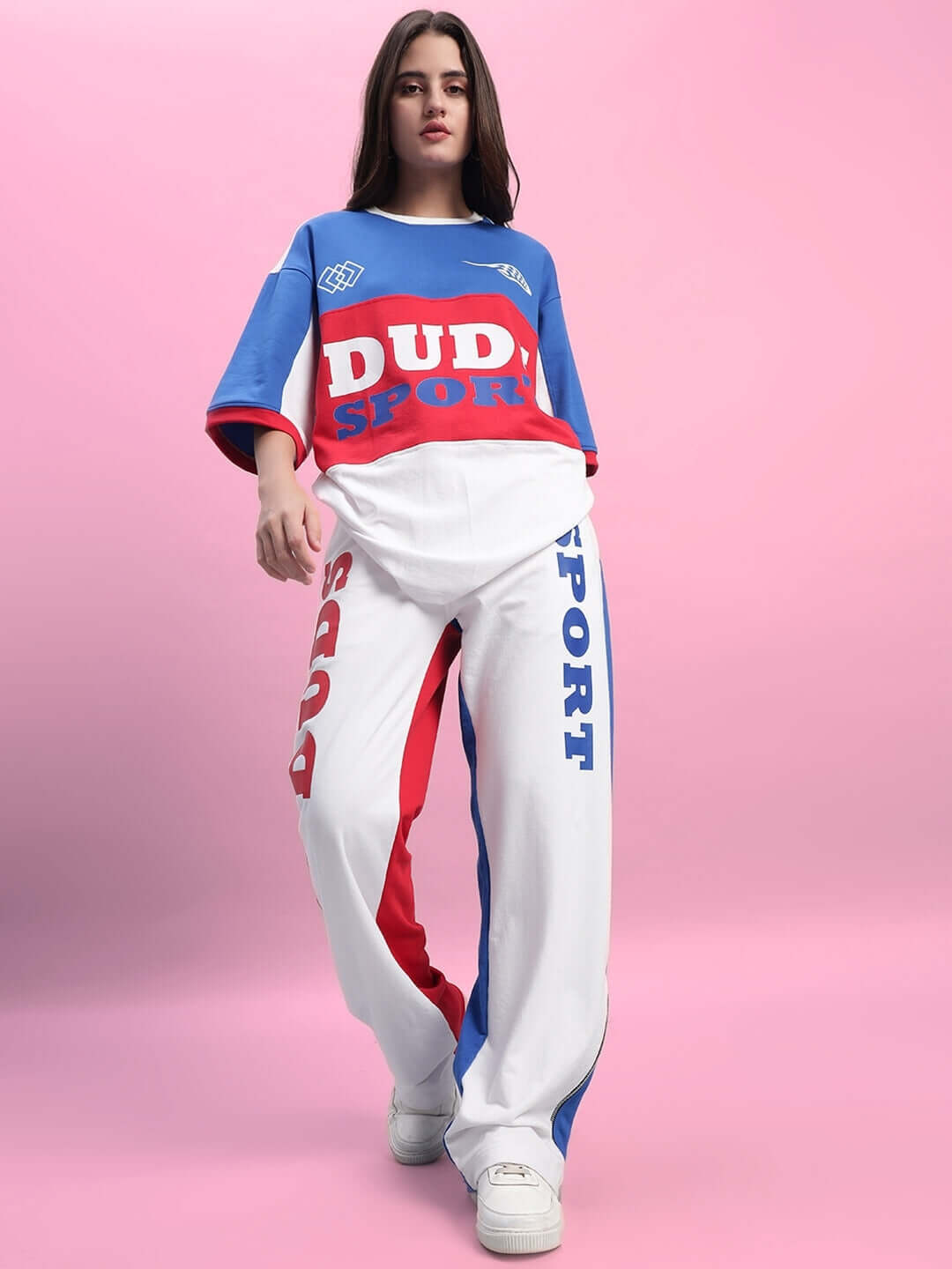 Model wearing WOMEN'S URBAN DRIFT CO-ORD SET MULTI with colorful oversized top and pants against pink background.
