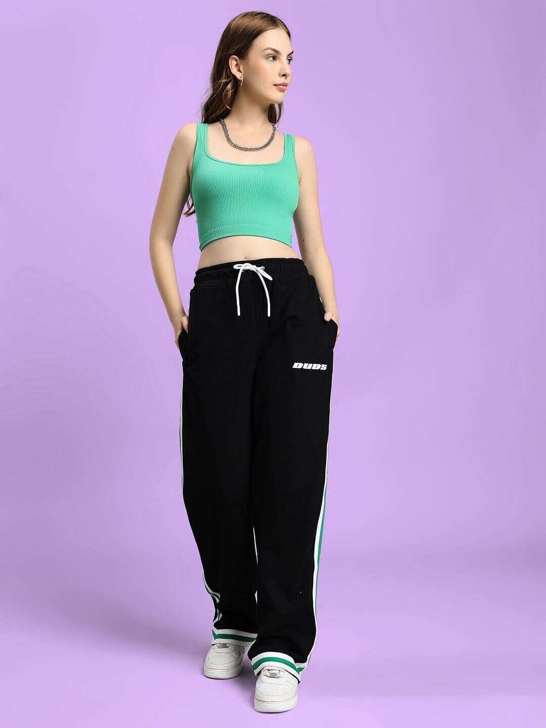 Woman wearing WOMEN'S VELO GREEN STRIPE RELAXED FIT JOGGER BLACK on a purple background with matching top.