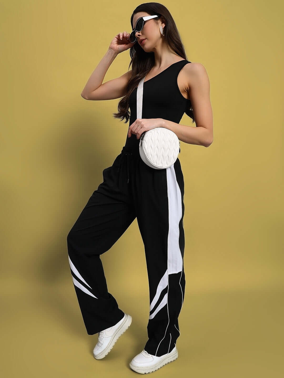 Woman in black and white parachute cargo pants with a stylish top, posing confidently. Perfect for customizable, versatile fashion styling.