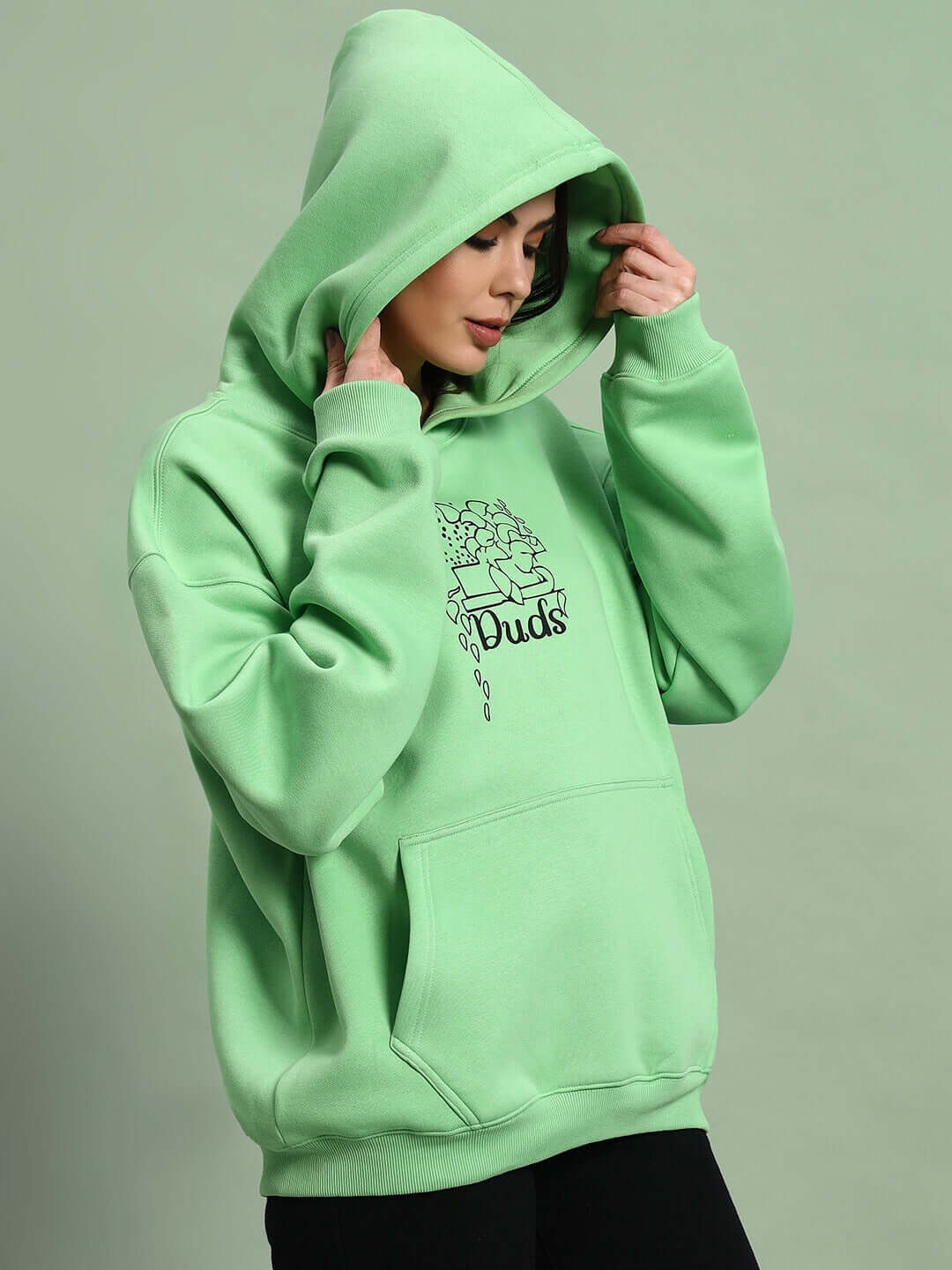 Woman wearing WOMEN VOODO FLEECE OVERSIZED HOODIE GREEN, showcasing its vibrant color and cozy fleece material.