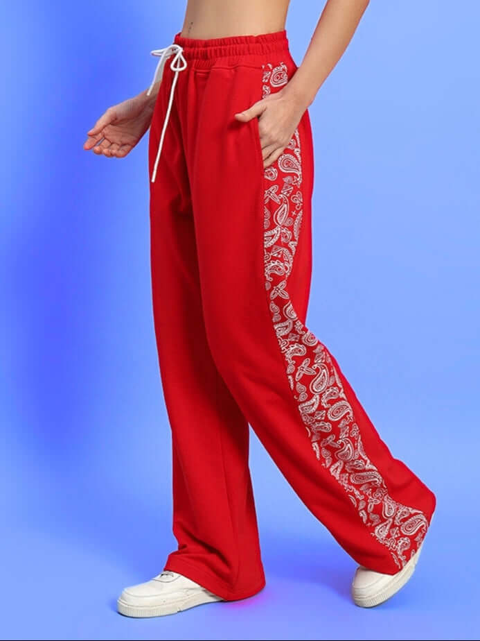 Model wearing red women's relaxed fit joggers with paisley design panel, showcasing casual comfort and style.