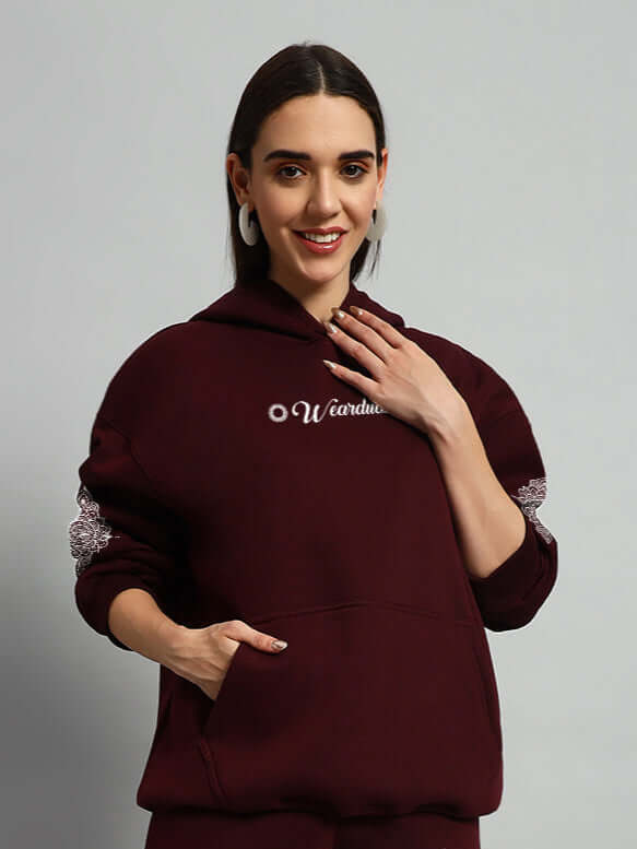 Woman wearing WOMENS YANTRA FLEECE HOODIE WINE showcasing cozy fleece texture and a deep wine hue for stylish comfort.