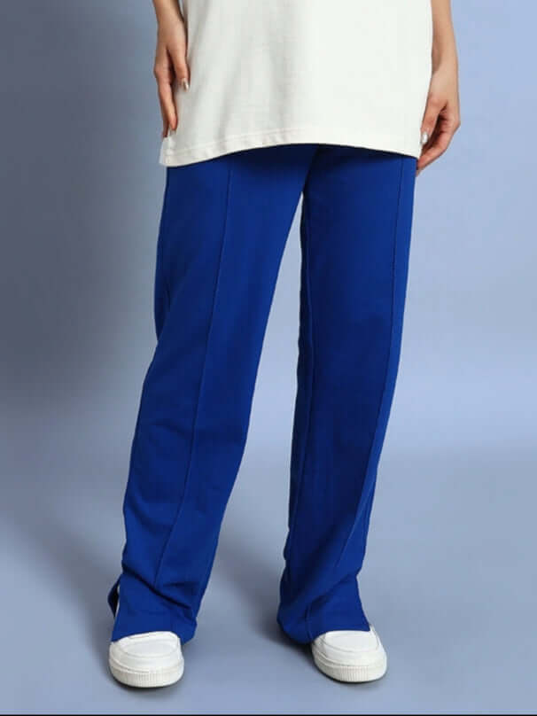 Woman wearing royal blue joggers with side slits and white sneakers.