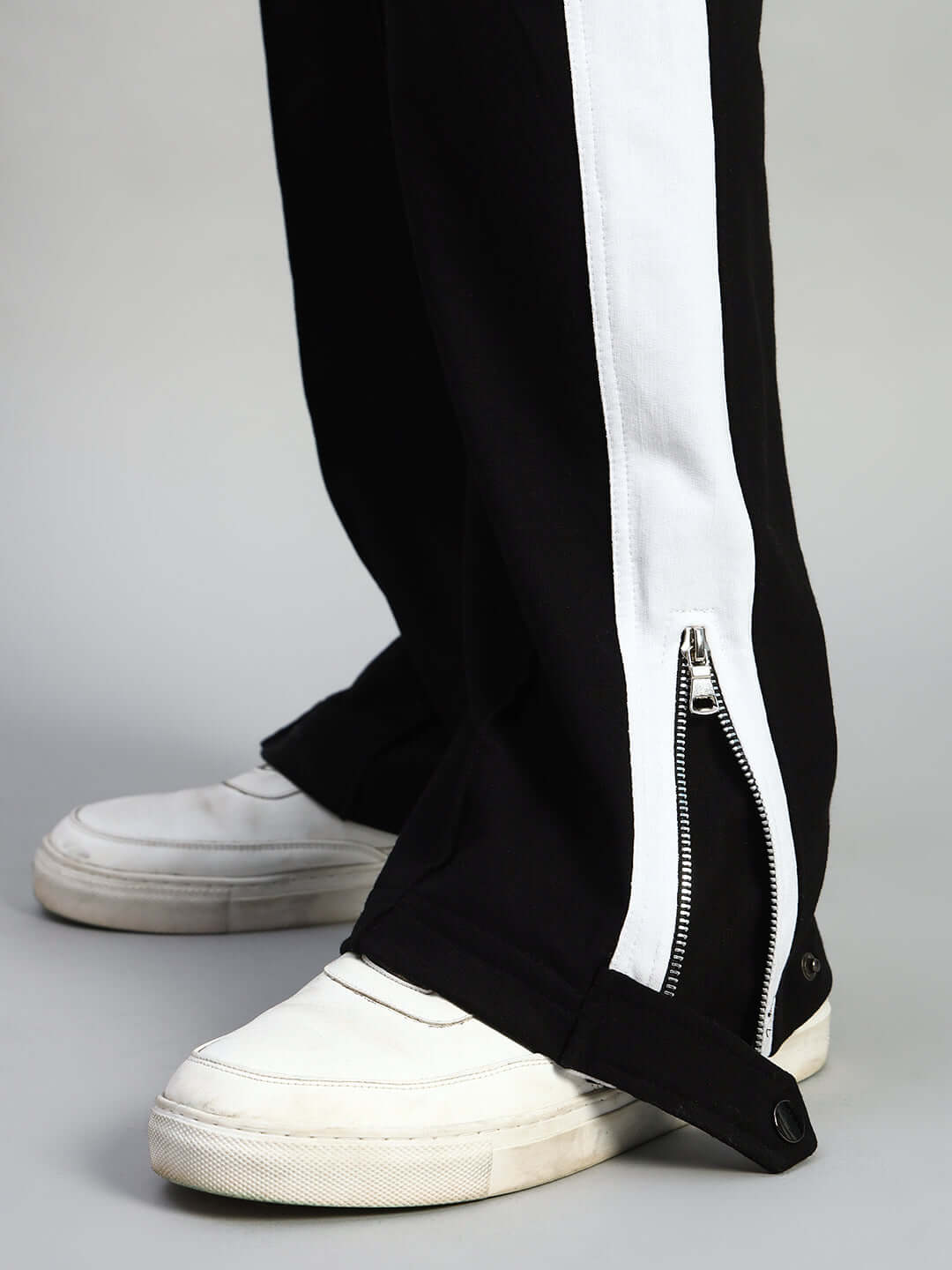 Close-up of black and white Wonder Slit Zipper Joggers featuring a stylish side zipper detail, paired with white sneakers.