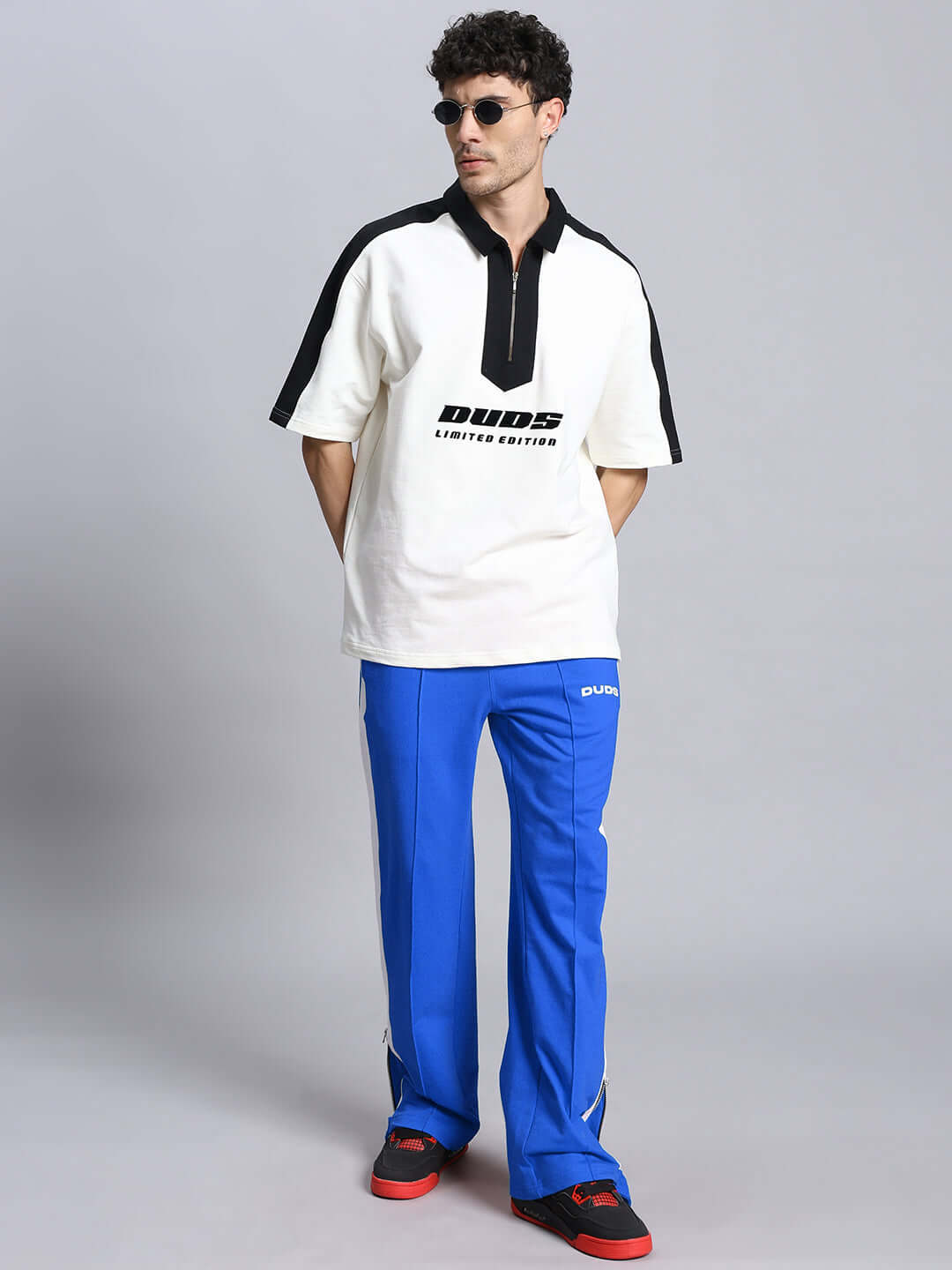 Model wearing Wonder Slit Zipper Joggers in blue and white, paired with a DUDS branded shirt and sunglasses.