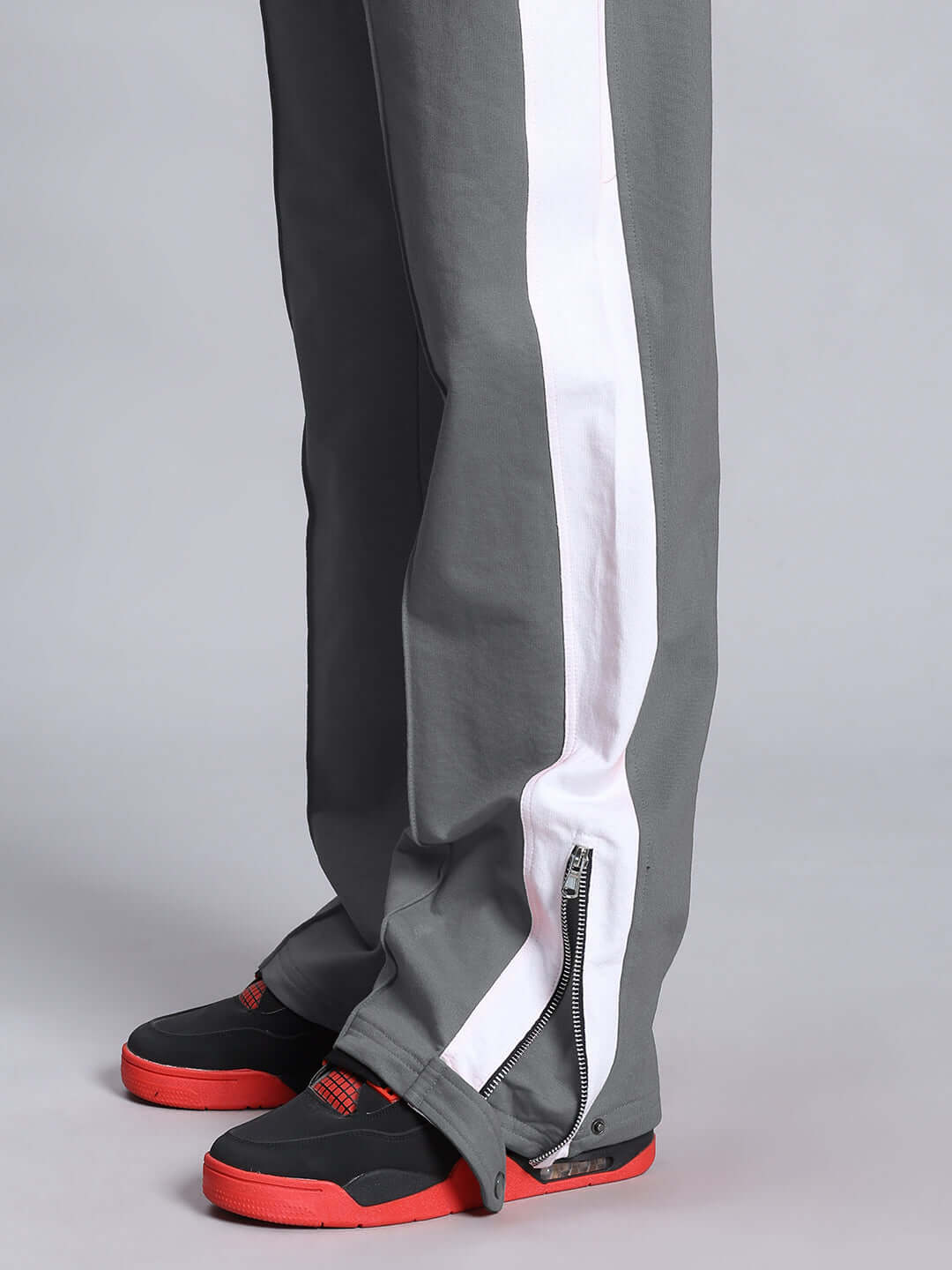 Side view of Wonder Slit Zipper Joggers in grey and white, featuring ankle zippers and sporty design, worn with black and red shoes.