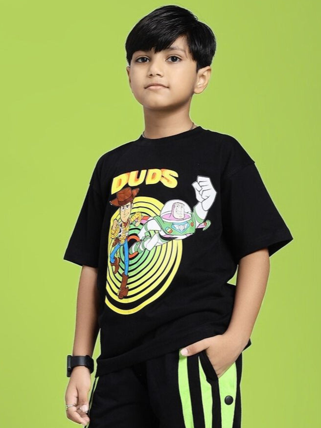 Child wearing WOODY BUZZ T-SHIRT FOR BOYS AND GIRLS BLACK with cartoon graphic design on green background.