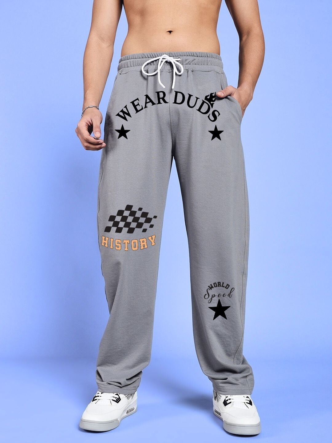Person wearing WORLD SPEED PRINTED RELAXED FIT JOGGERS GREY with design details on a blue background.