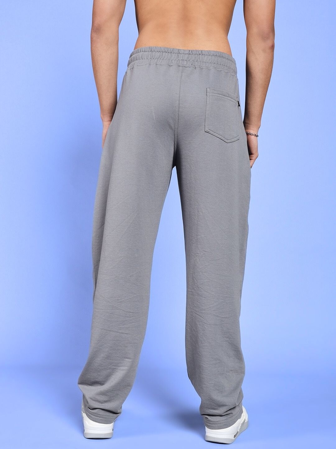 Back view of WORLD SPEED PRINTED RELAXED FIT JOGGERS GREY on model against blue background.