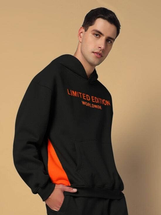 Man wearing WORLDWIDE FLEECE HOODIES BLACK, featuring a limited edition design with orange accents, perfect for casual streetwear style.