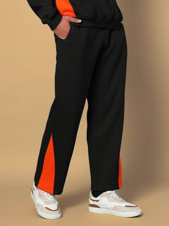 Model wearing black fleece joggers with orange accents and white sneakers, showcasing comfortable fit and stylish design
