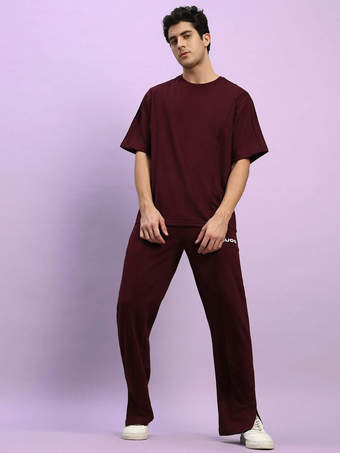 Man wearing ZION RELAXED FIT CO-ORD SET MAROON standing against a purple background showcasing streetwear style.