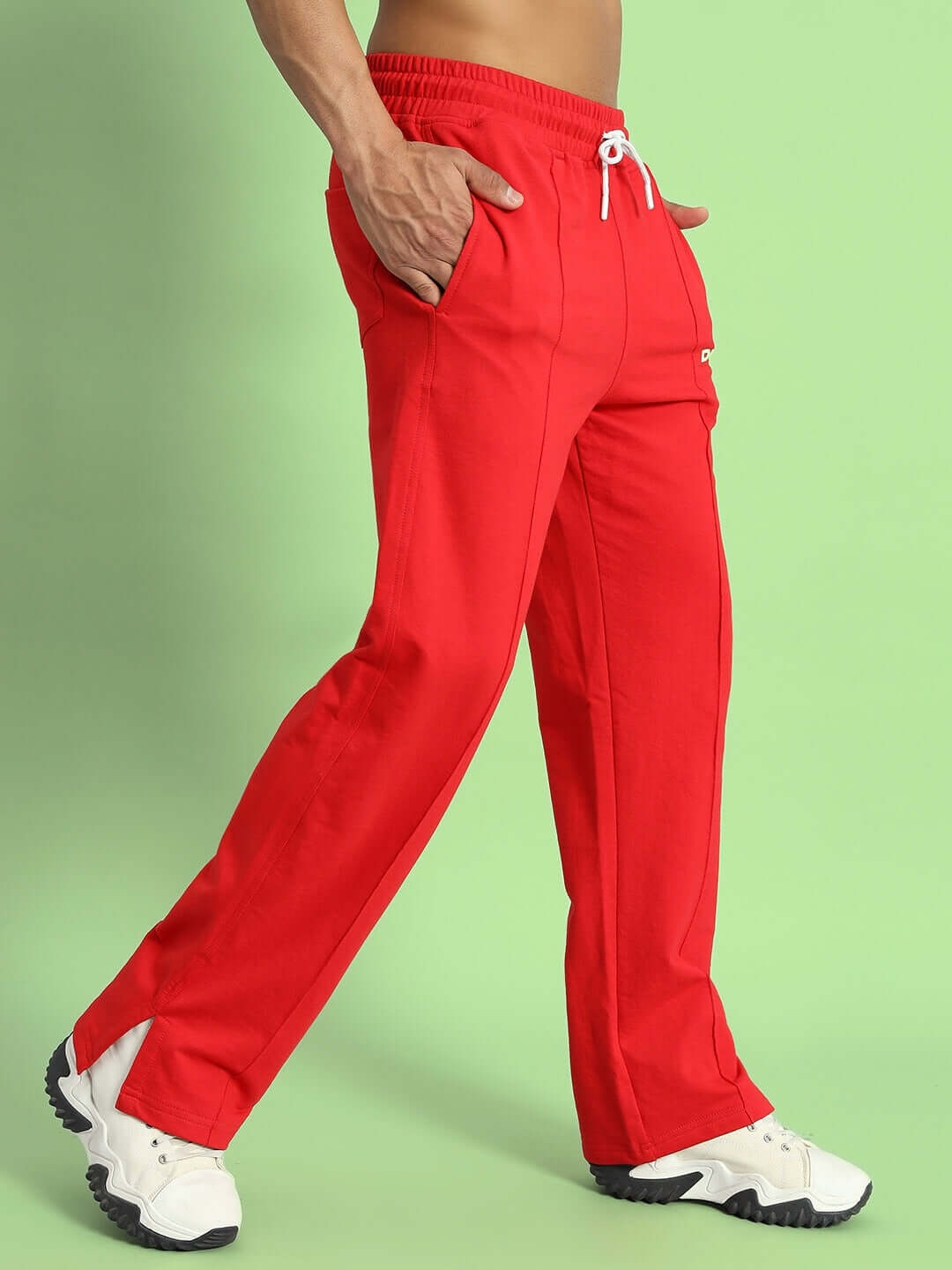 Red Zion joggers with side slits, designed by DUDS, shown on green background, highlighting customized fit options for versatile wear.