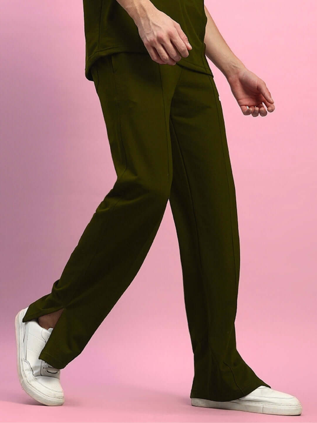 Man wearing olive green ZION SIDE SLIT JOGGERS from DUDS, showcasing side slits and comfortable fit against a pink background.