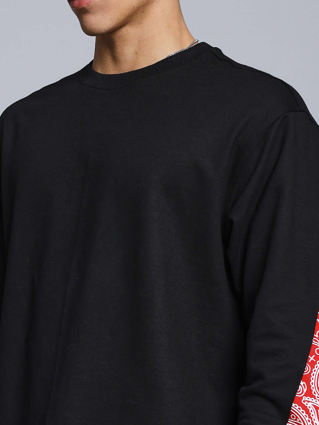 Man wearing ZONEX black sweatshirt with red sleeve detail, made of premium cotton French Terry. Ideal for casual wear.