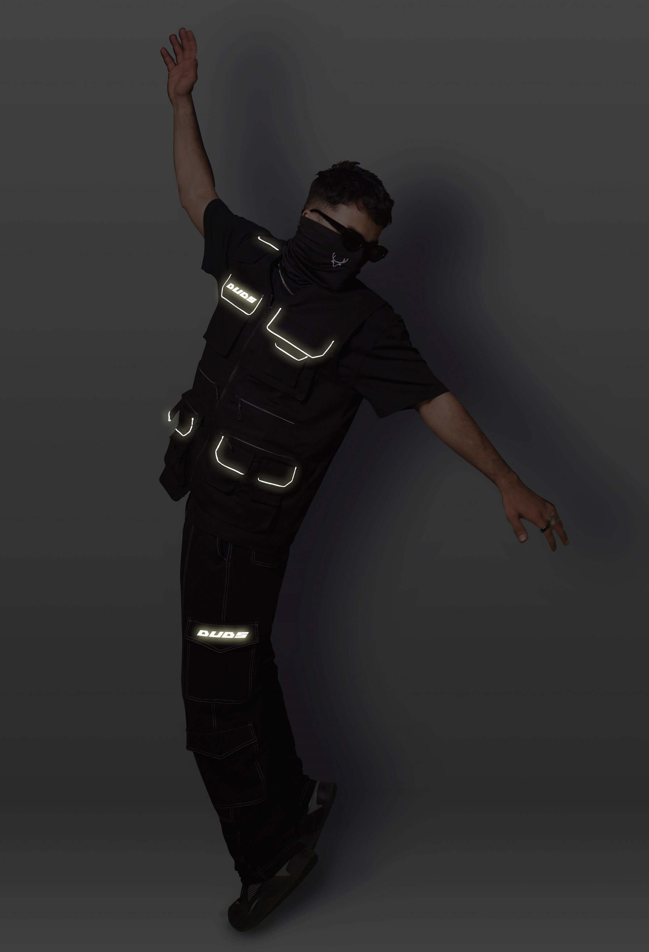 Model wearing Multi Pockets Reflector Cargo Vest, showcasing utility design and modern streetwear style with multiple reflective strips.