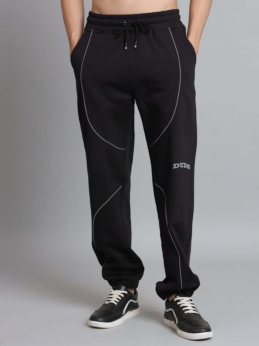 Black fleece jogger with reflective armor design and white detailing, worn by model in sneakers. Comfortable and stylish activewear.