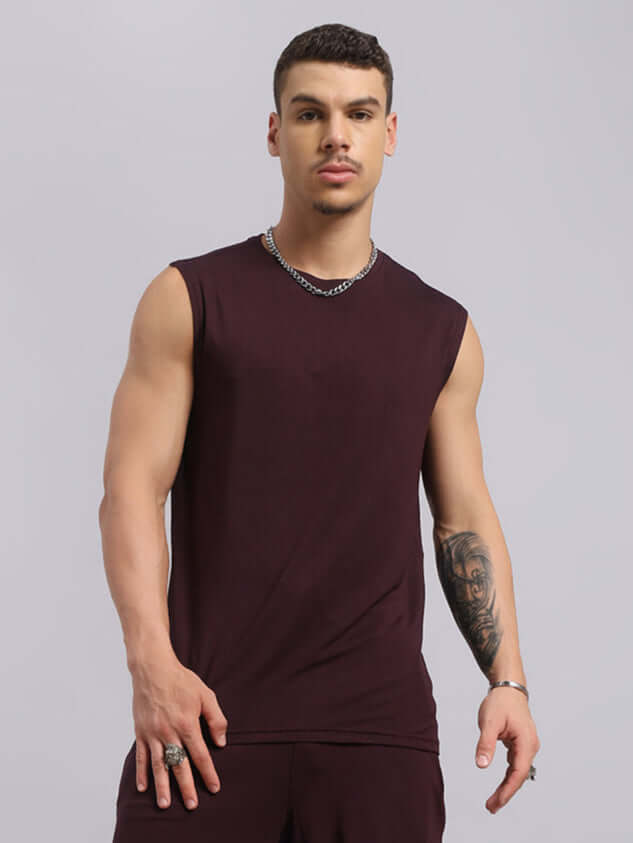 Man wearing a wine-colored Strength Freak fitness t-shirt, showcasing sleeveless design and breathable cotton fit for summer workouts.