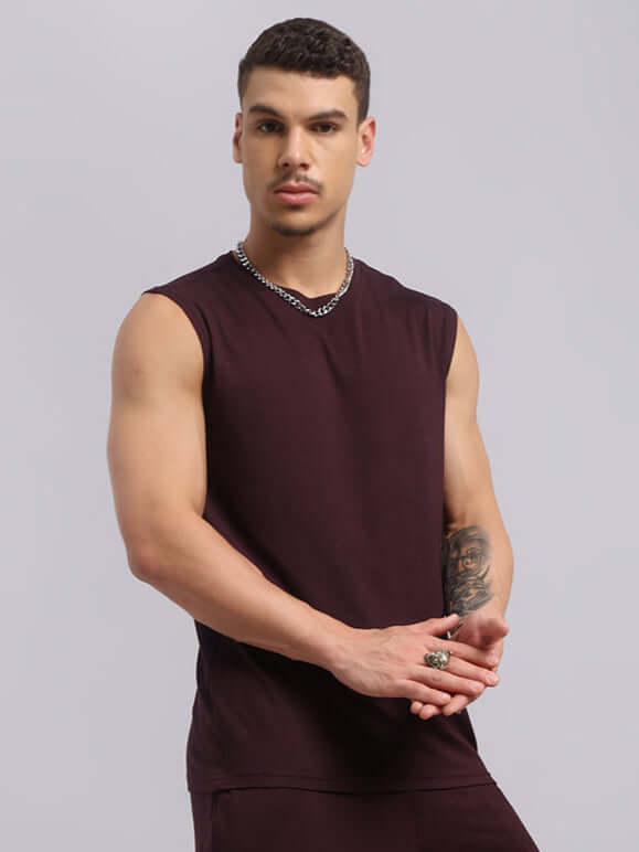 Model wearing a Strength Freak Fitness sleeveless t-shirt in wine color, showcasing a trendy, comfortable summer look with a relaxed fit.