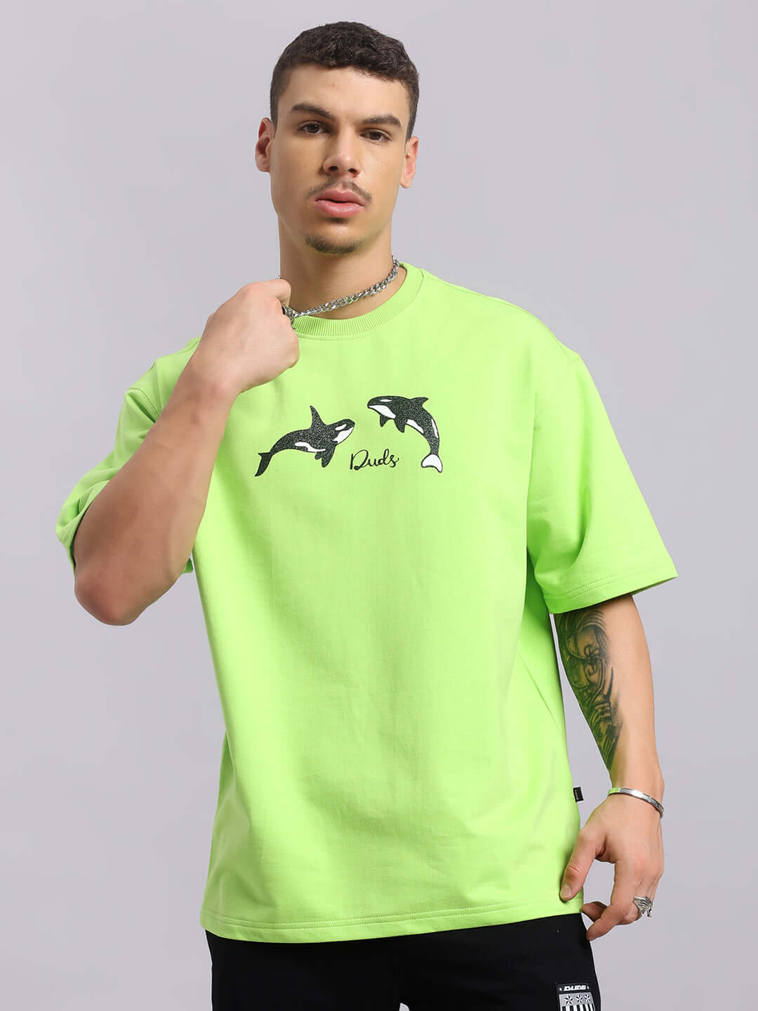 Model wearing ORCAS OVER-SIZED T-SHIRT in neon green, featuring orca print. Made of premium cotton elastane blend. Bio-washed for softness.