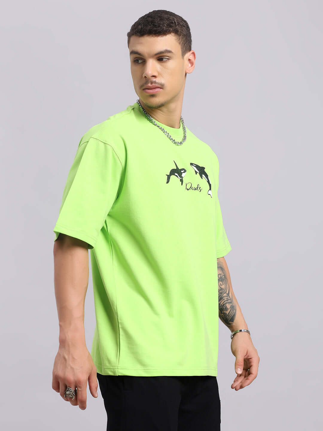 Model wearing neon green Orcas oversized T-shirt made from premium cotton blend, featuring orca graphics and round neckline.