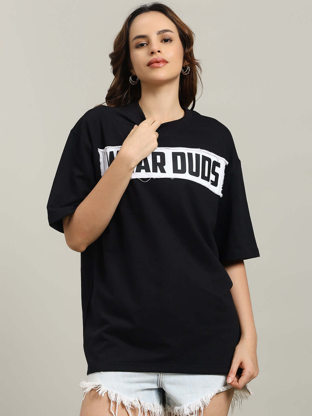 Model wearing black oversized women's Harley designer t-shirt made of 97% cotton and 3% elastane, paired with denim shorts.