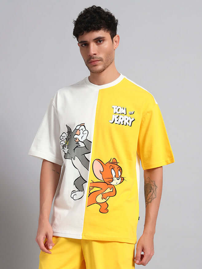 Man wearing an oversized Tom & Jerry t-shirt in off-white and yellow, showcasing trendy summer fashion with cartoon characters.