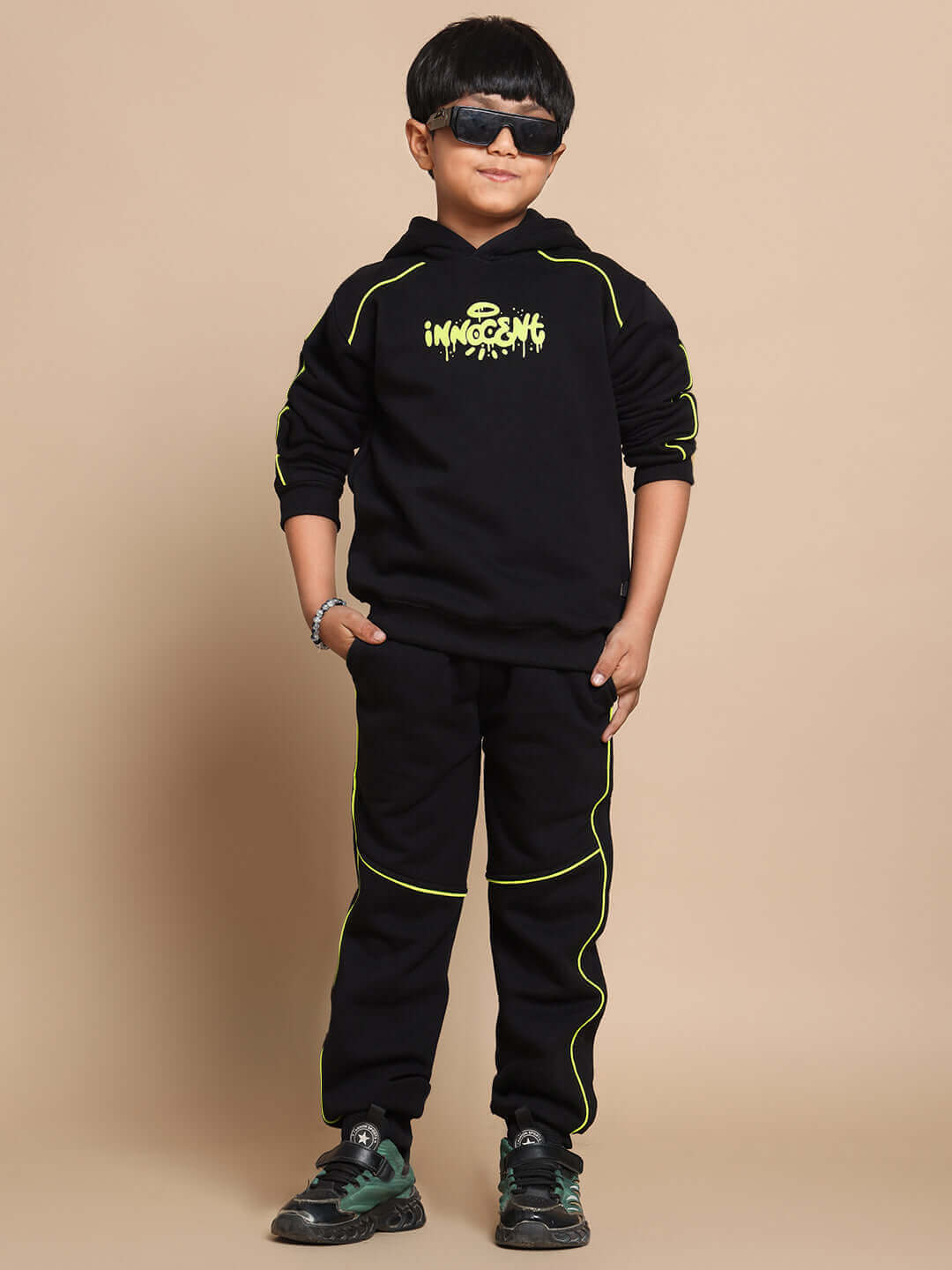 Boy wearing Innocent oversized black hoodie with neon accents, paired with matching joggers and sneakers.